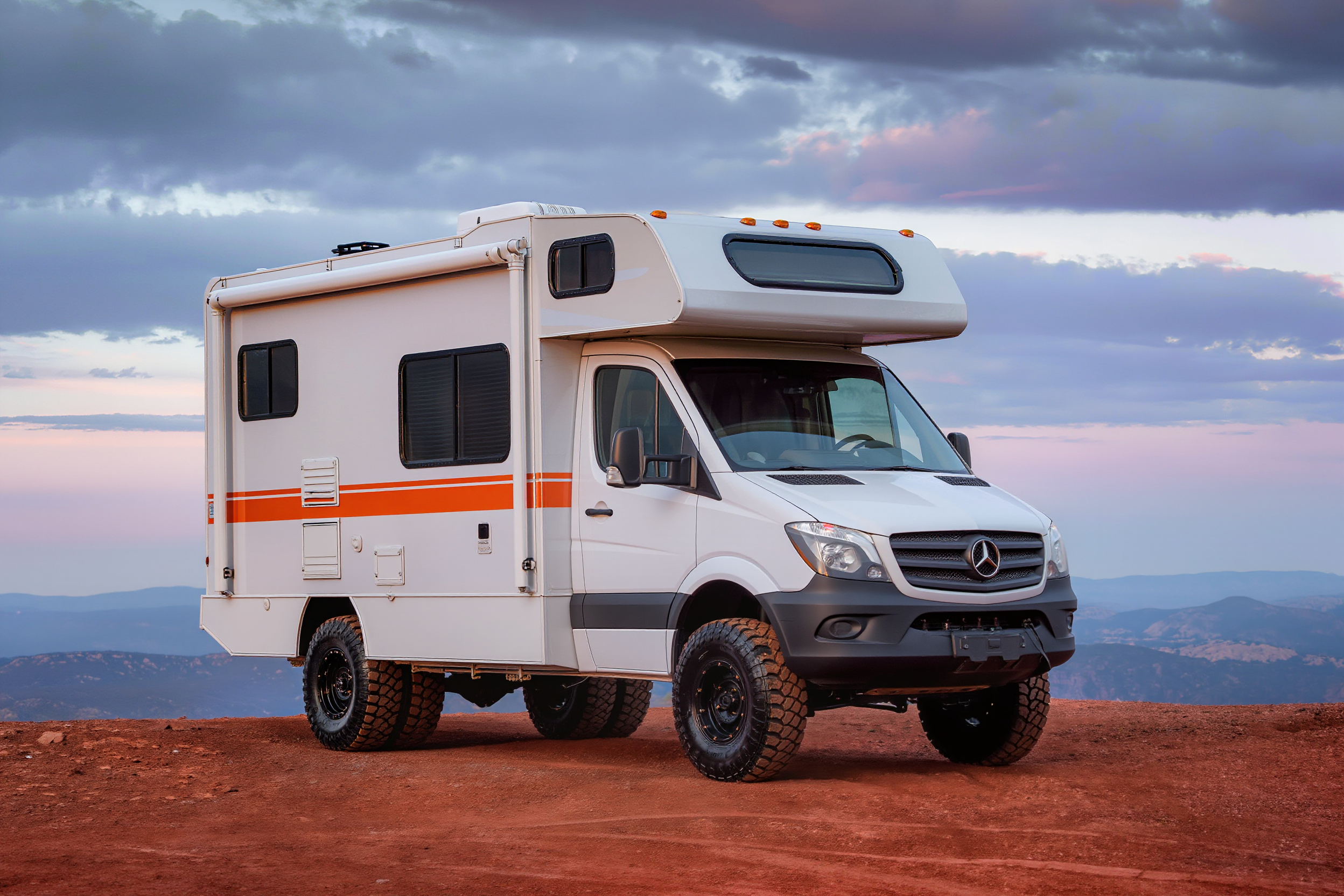 White and orange 4x4 Sprinter camper van on a high country overlook